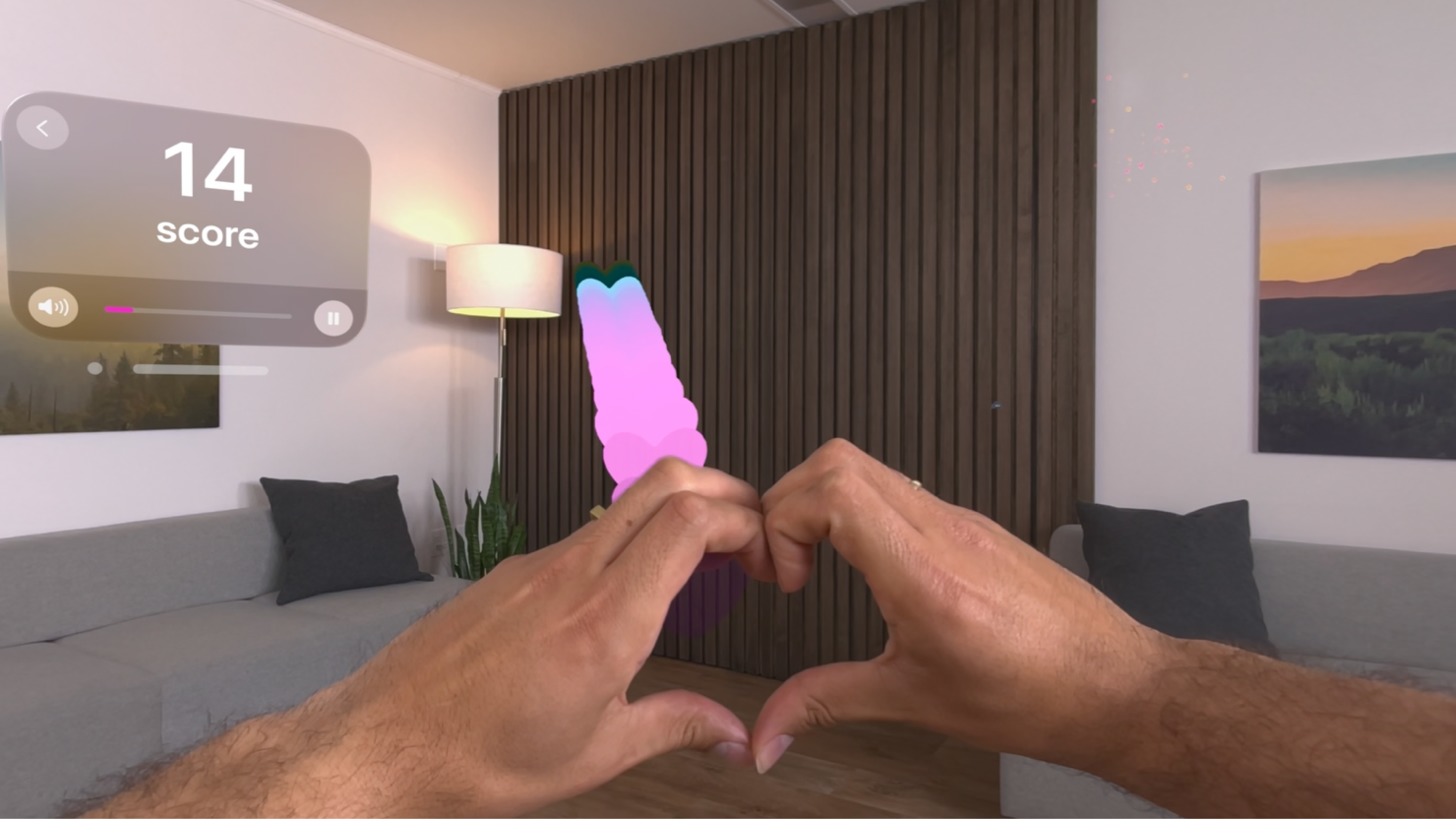 A screenshot of a person's hands performing a custom gesture, placing the two hands together to form a heart, while playing a visionOS game.