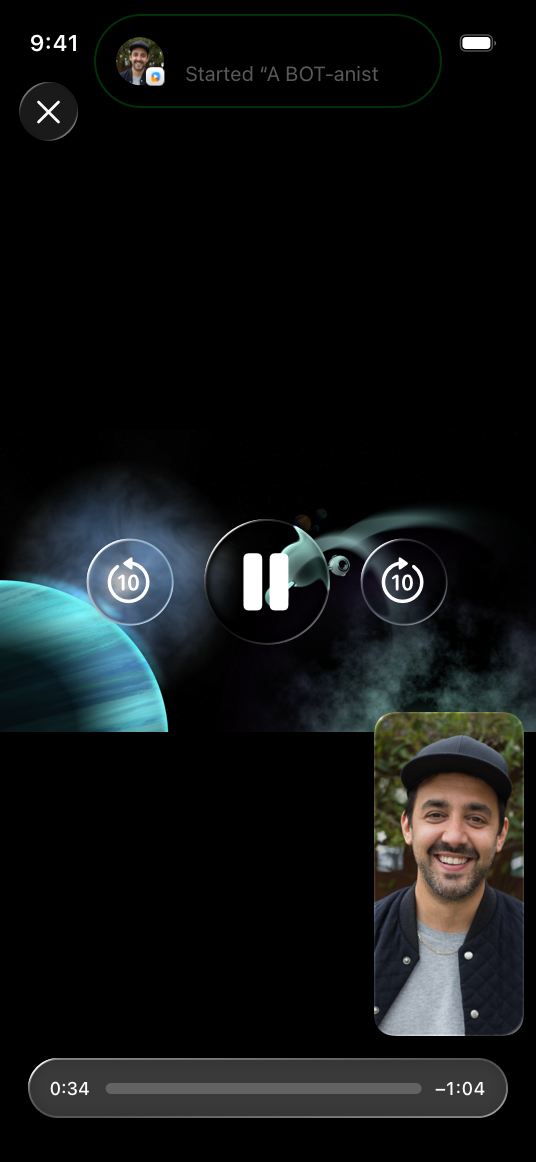 A screenshot of the TV app on iPhone. The screen shows a video with SharePlay turned on. The area around the Dynamic Island includes an icon of the person being shared with, badged with the app logo, and the text 'Started A BOT-anist'. A FaceTime call with the SharePlay recipient sits in an overlay in the lower right corner of the screen.
