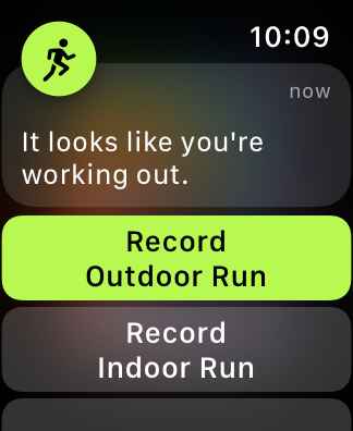 A screenshot of a Workout app screen on Apple Watch. The screen includes text that reads 'It looks like you're working out', above buttons in a scrolling list. The two visible buttons are titled 'Record Outdoor Run' and 'Record Indoor Run'.