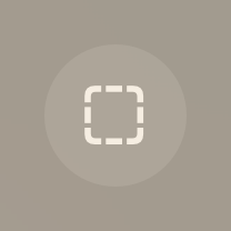 An image of a circular button that contains an icon of an outlined square with rounded corners. The button background is very dark and the outline is light.